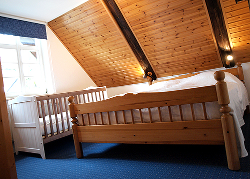 Schlafzimmer mit Doppelbett und Kinderbett in der Ferienwohnung "Heuboden".